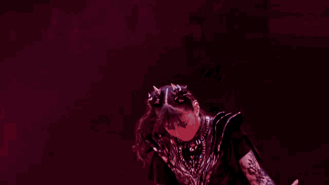 a woman in a black dress with spikes on her hair is dancing on a stage .