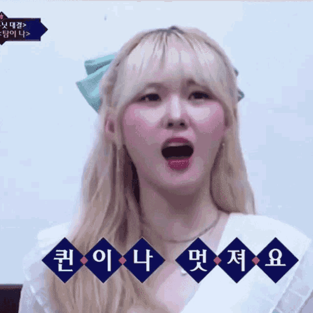 a girl with blonde hair is making a funny face with her mouth open in korean