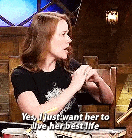 a woman is talking into a microphone while sitting at a table with a book .