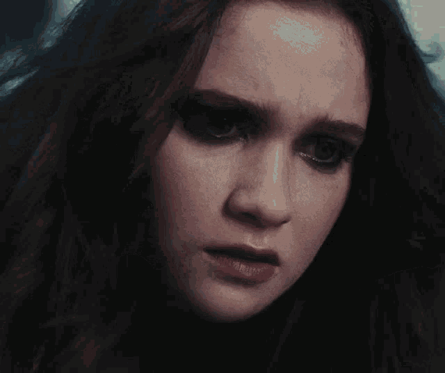 a close up of a woman 's face with a sad expression