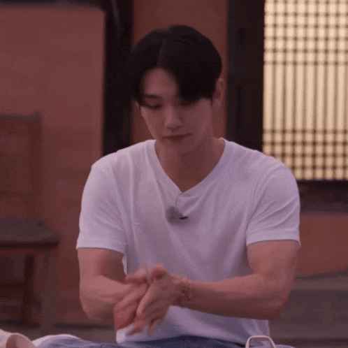 a man wearing a white t-shirt is rubbing his hands
