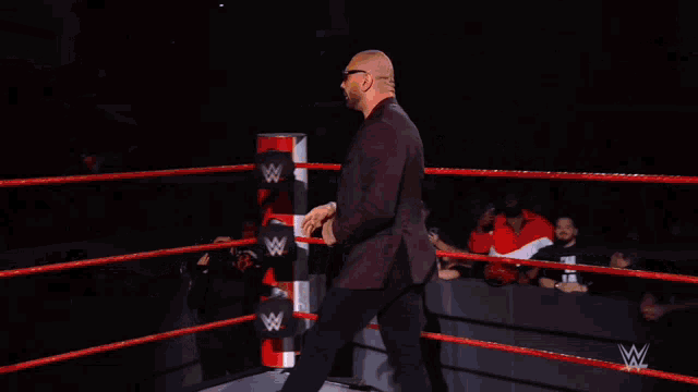 a man in a suit and sunglasses is walking in front of a wrestlemania sign