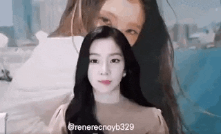 a woman with long black hair is standing in front of a painting of another woman .