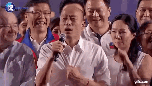 a man is holding a microphone in front of a group of people .