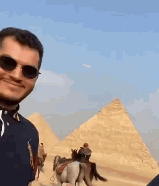 a man wearing sunglasses and a polo shirt covering his face with his hand