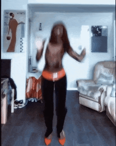 a woman is dancing in a living room in front of a chair and a couch .