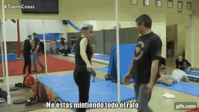 a man and a woman are standing in a gym and the man is saying me estás mintiendo todo el rato