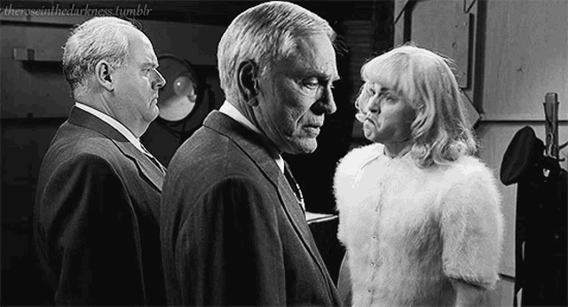 a man in a suit and tie stands next to a woman in a white fur coat .