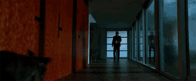 a person standing in a hallway with a dog looking out the window