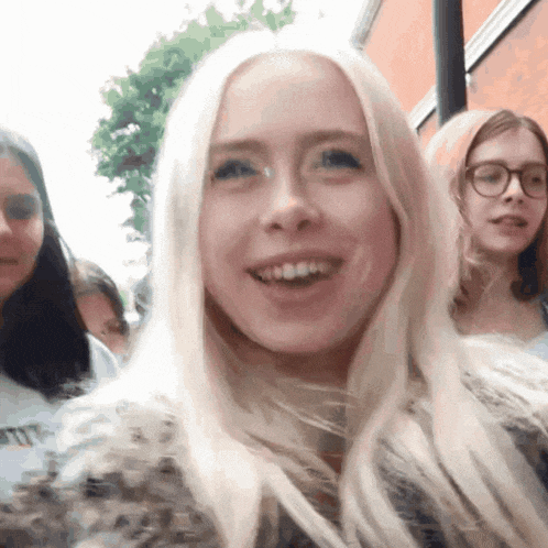 a woman with blonde hair and glasses is smiling in front of two other women