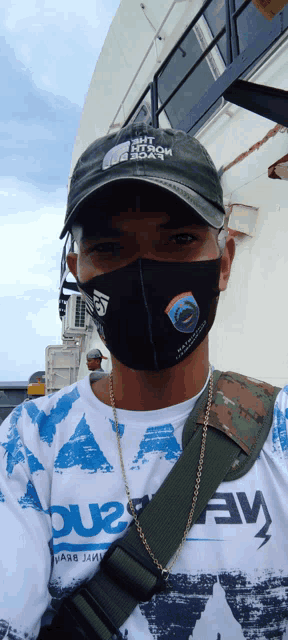 a man wearing a face mask and a hat with the word north face on it