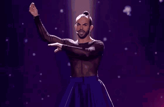 a man with a beard is dancing on a stage with his hands outstretched .