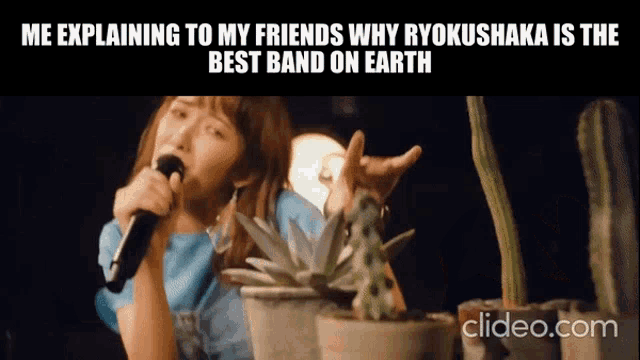 a woman singing into a microphone next to potted plants