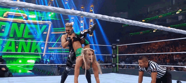 a woman is doing a handstand in a wrestling ring with a referee watching .