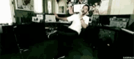 a man in a white shirt is singing into a microphone in a recording studio .