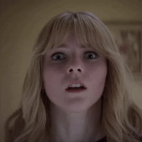 a woman with blonde hair and bangs is making a surprised face with her mouth open .