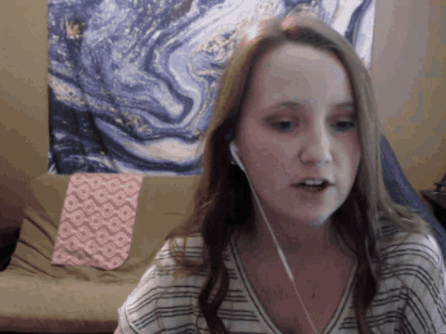 a woman wearing earbuds is sitting in front of a painting