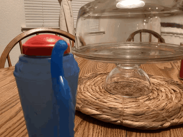 a blue water bottle sits on a table next to a glass dome
