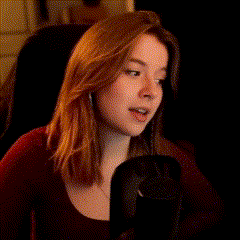 a woman with long red hair is sitting in front of a microphone and talking into it .