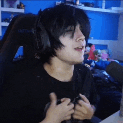 a person wearing headphones and a black shirt is sitting in a gaming chair .