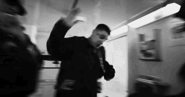 a black and white photo of a man standing next to a police officer in a room .