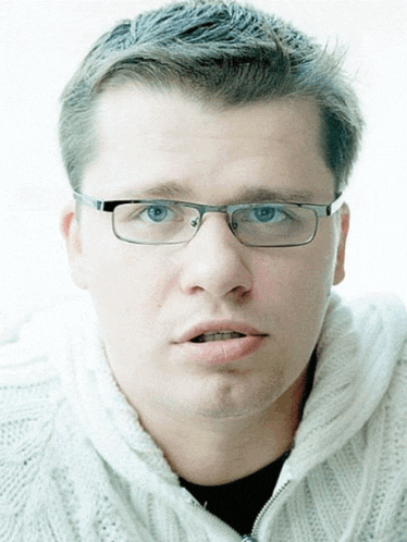 a man wearing glasses and a white sweater
