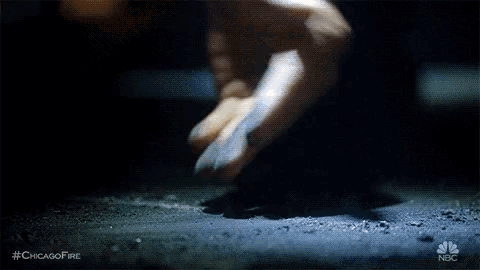 a close up of a person 's hand reaching out towards a pile of dirt .