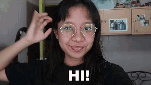 a girl wearing glasses and a black shirt with hi written on it