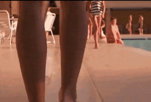 a woman 's legs are shown as she walks by a pool