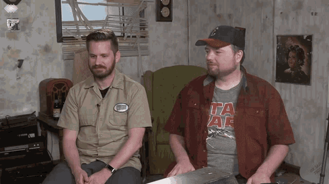 two men are sitting in a room with one wearing a shirt that says star wars