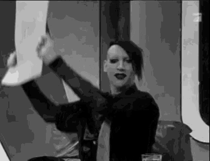 a black and white photo of marilyn manson holding a piece of paper in her hands .