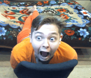 a man in an orange shirt is laying on his stomach with his mouth open