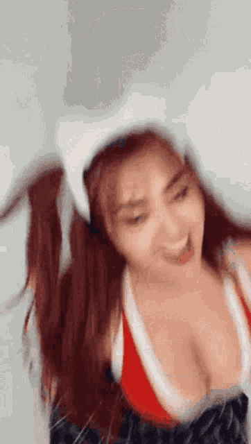 a woman wearing a cat ear headband and a red top is smiling .