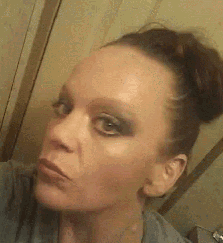 a woman is taking a selfie with her hair in a bun and looking at the camera .