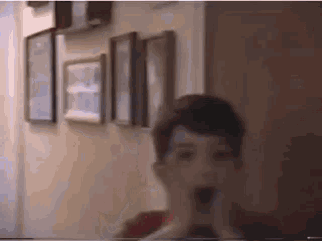 a young boy is sitting at a table with his hands on his face in front of a wall of pictures .