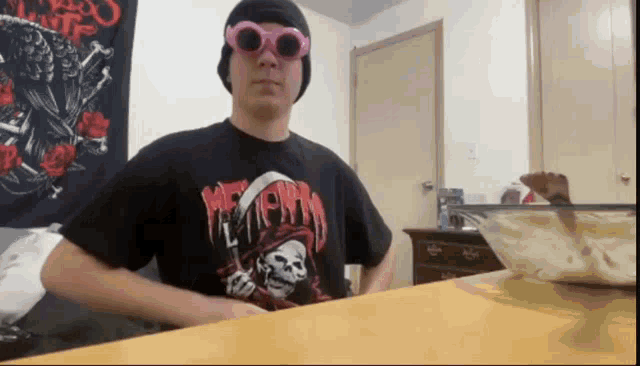 a man wearing a shirt that says misfits is standing in front of a table