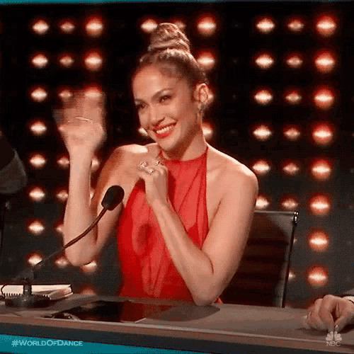 a woman in a red dress is sitting at a table with a microphone in front of her .