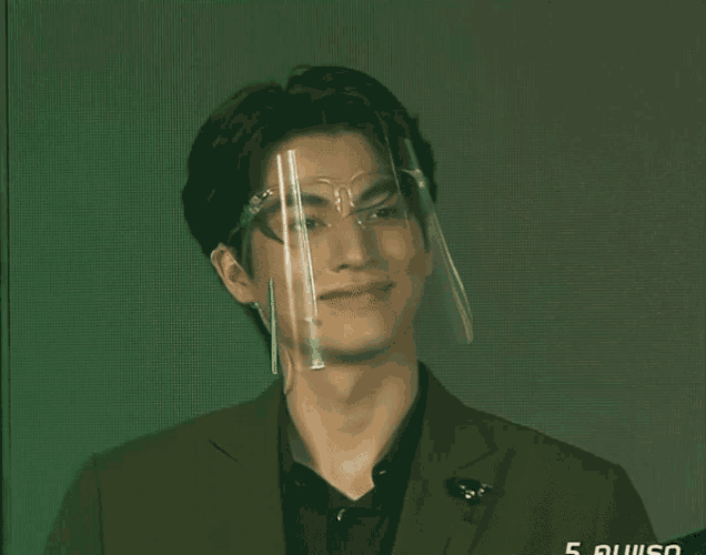 a man wearing a face shield and a suit is smiling