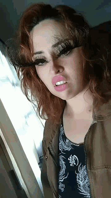 a woman wearing false eyelashes and pink lipstick is making a face