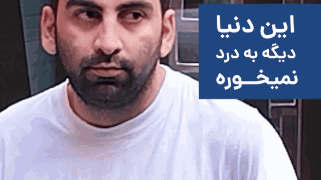 a man with a beard is standing in front of a blue sign that says ' iran dunia ' on it