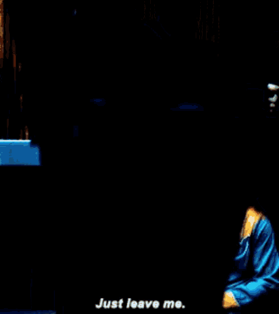 a person is laying on the floor with a blanket on their back and says `` just leave me . ''