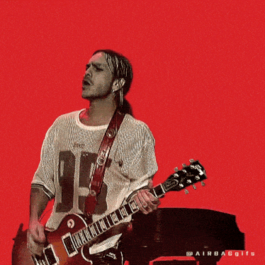 a man is playing a gibson guitar and wearing a white shirt with the number 19 on it