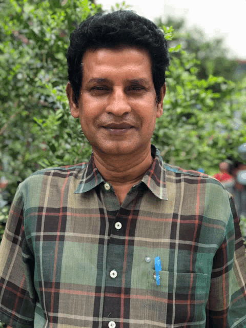 a man wearing a plaid shirt with a blue pen in his pocket