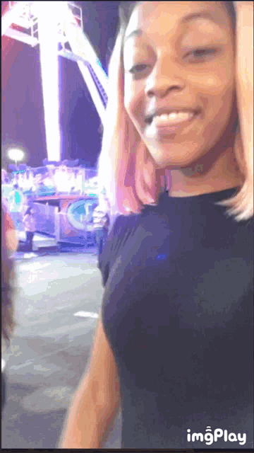a woman is smiling in front of a ferris wheel and a sign that says img play