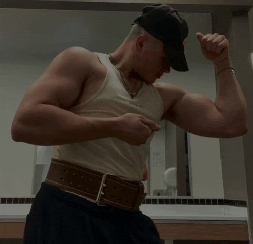 a man flexing his muscles in front of a bathroom mirror