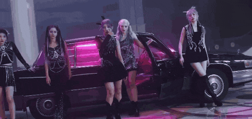 a group of girls are standing next to a black limousine .