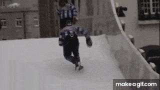 a person is ice skating on a snowy slope while another person watches .