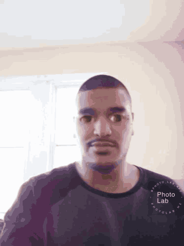 a man wearing glasses and a black shirt has a photo lab sticker on his shirt