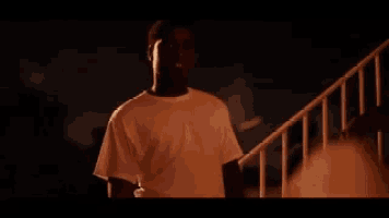 a man in a white shirt is standing on a set of stairs at night