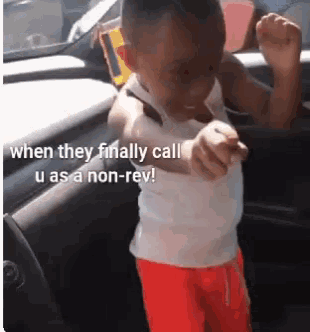 a little boy in a white tank top and orange shorts is dancing in a car .